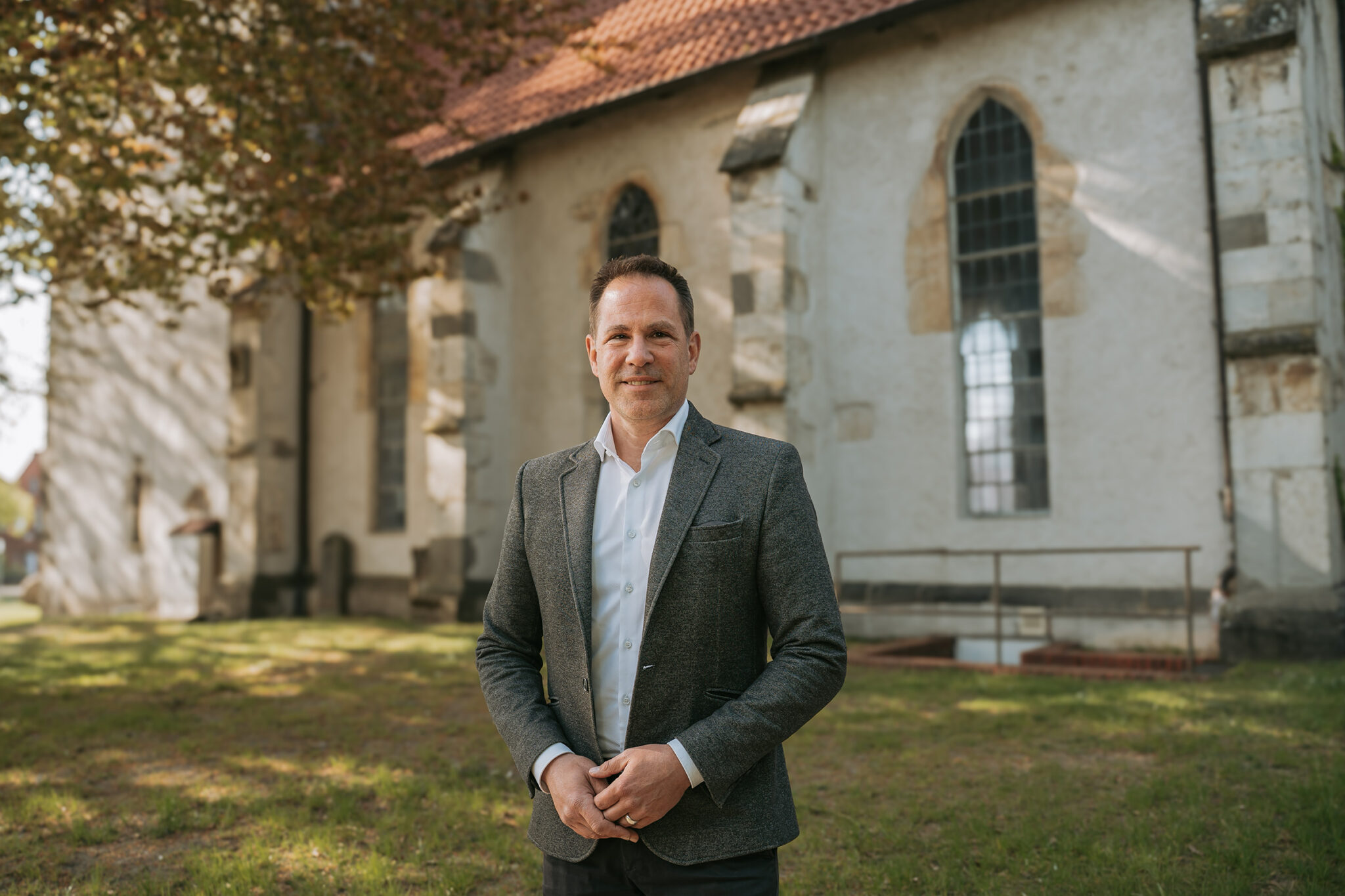 Portraitbild von Tim Mithöfer vor einer Kirche